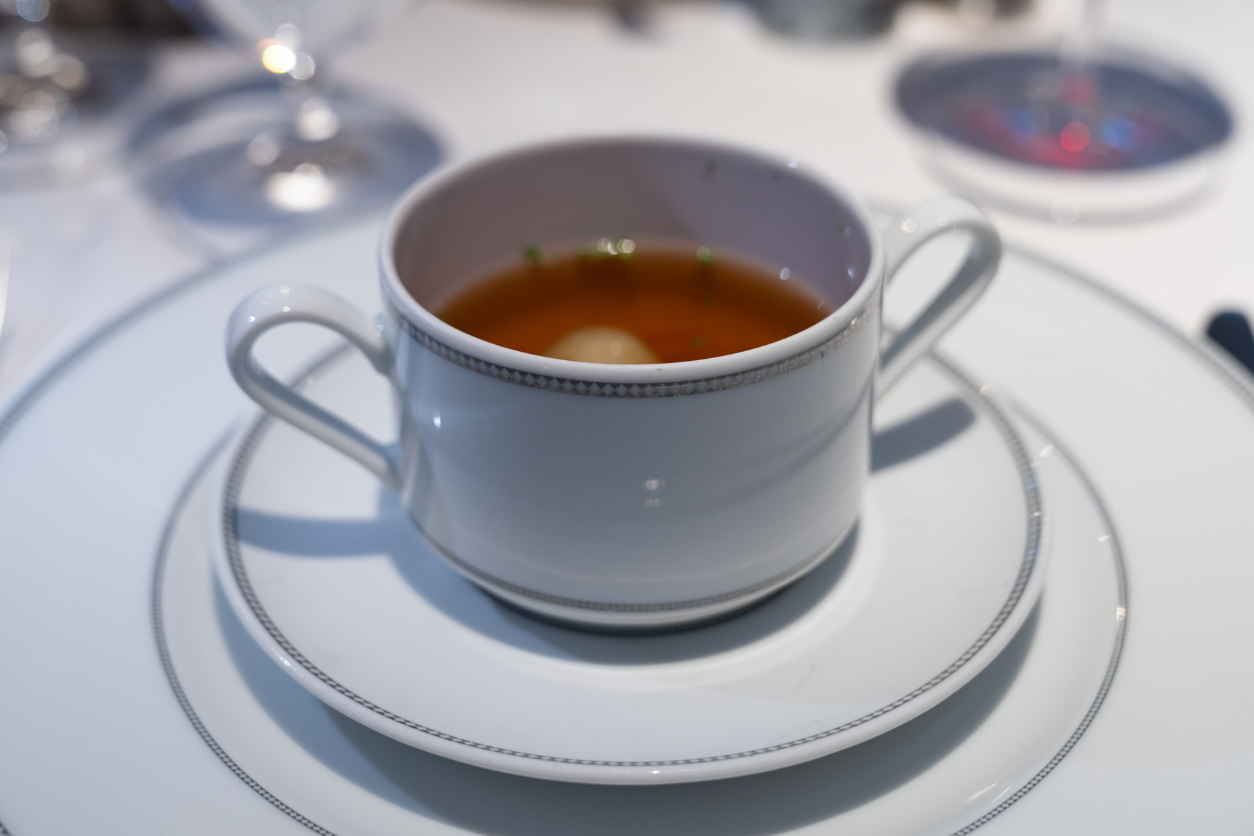Chicken consommé with matzo balls, vegetables, and chives.