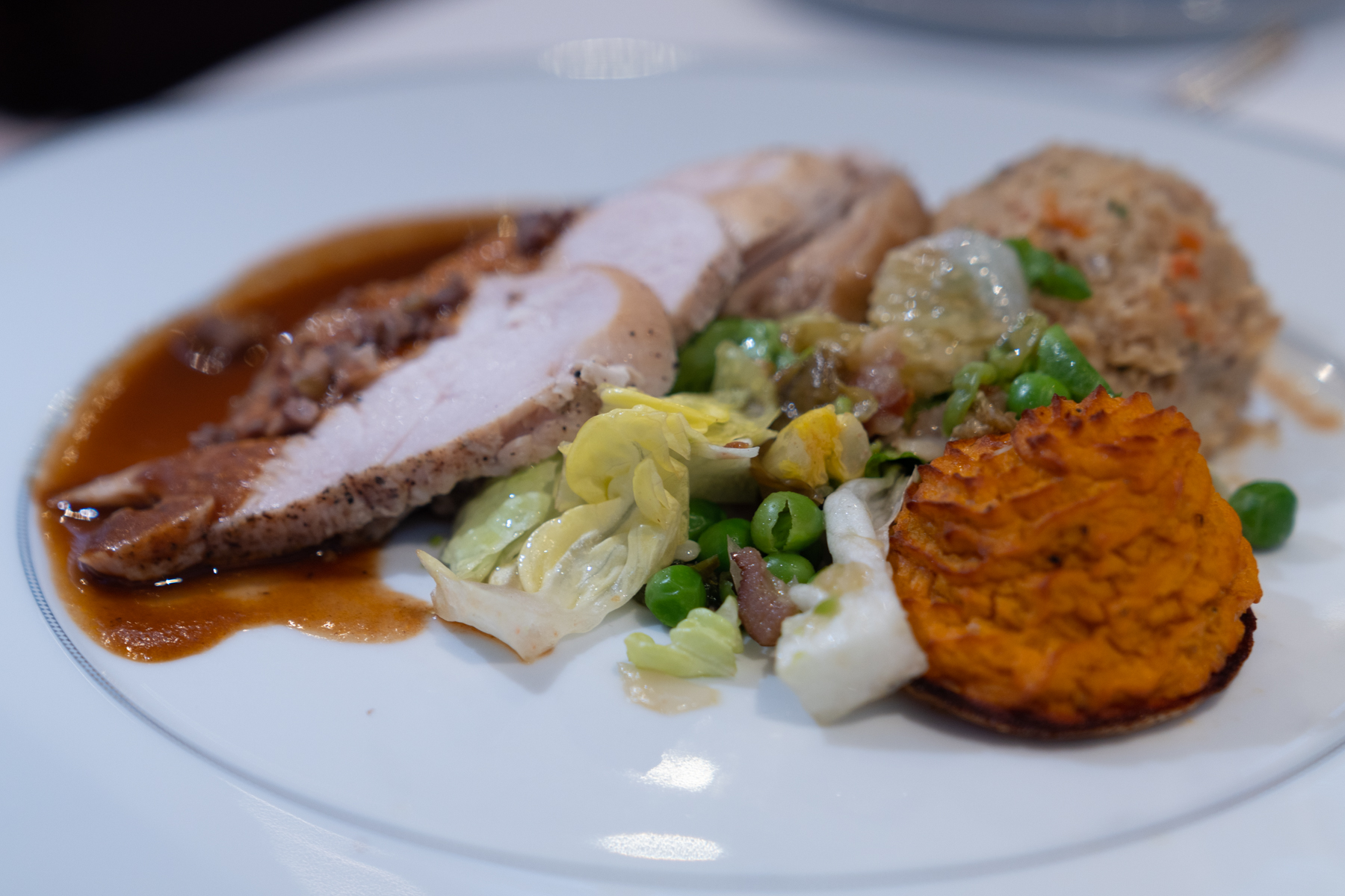 Roast turkey with gravy, chestnut stuffing, sweet potato rosette, green peas, and orange and cranberry relish.