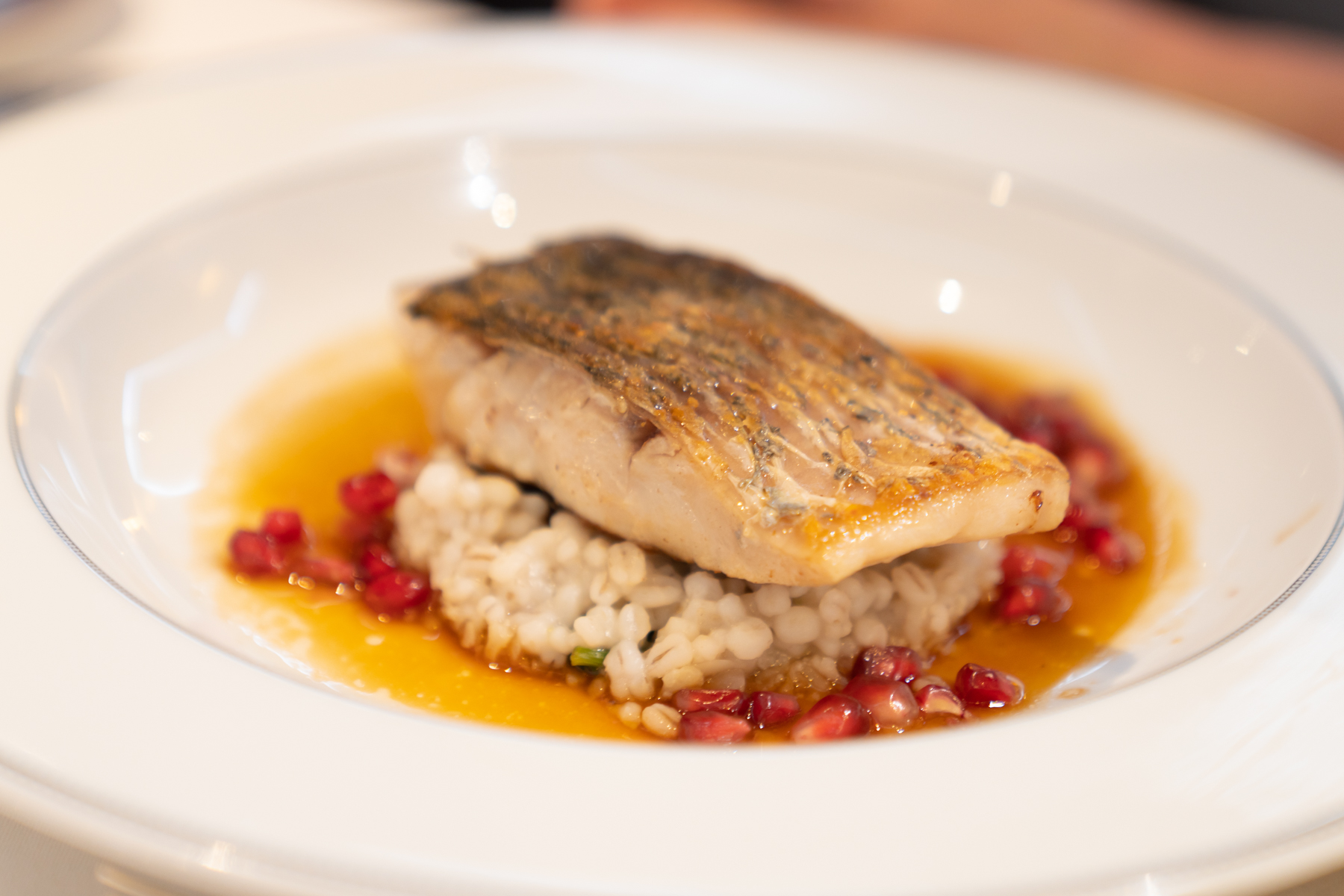Grilled barramundi fillet with cauliflower rice barley, spinach, and pomegranate vinaigrette.