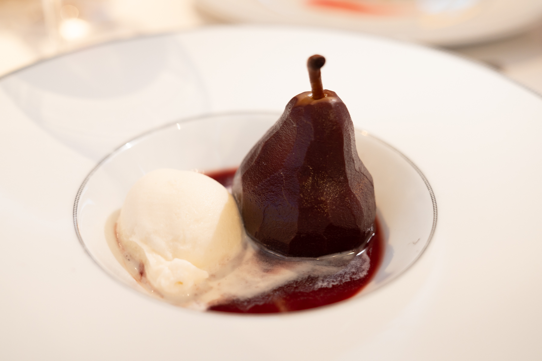 Spiced red wine poached pear with cashew and vanilla ice-cream.