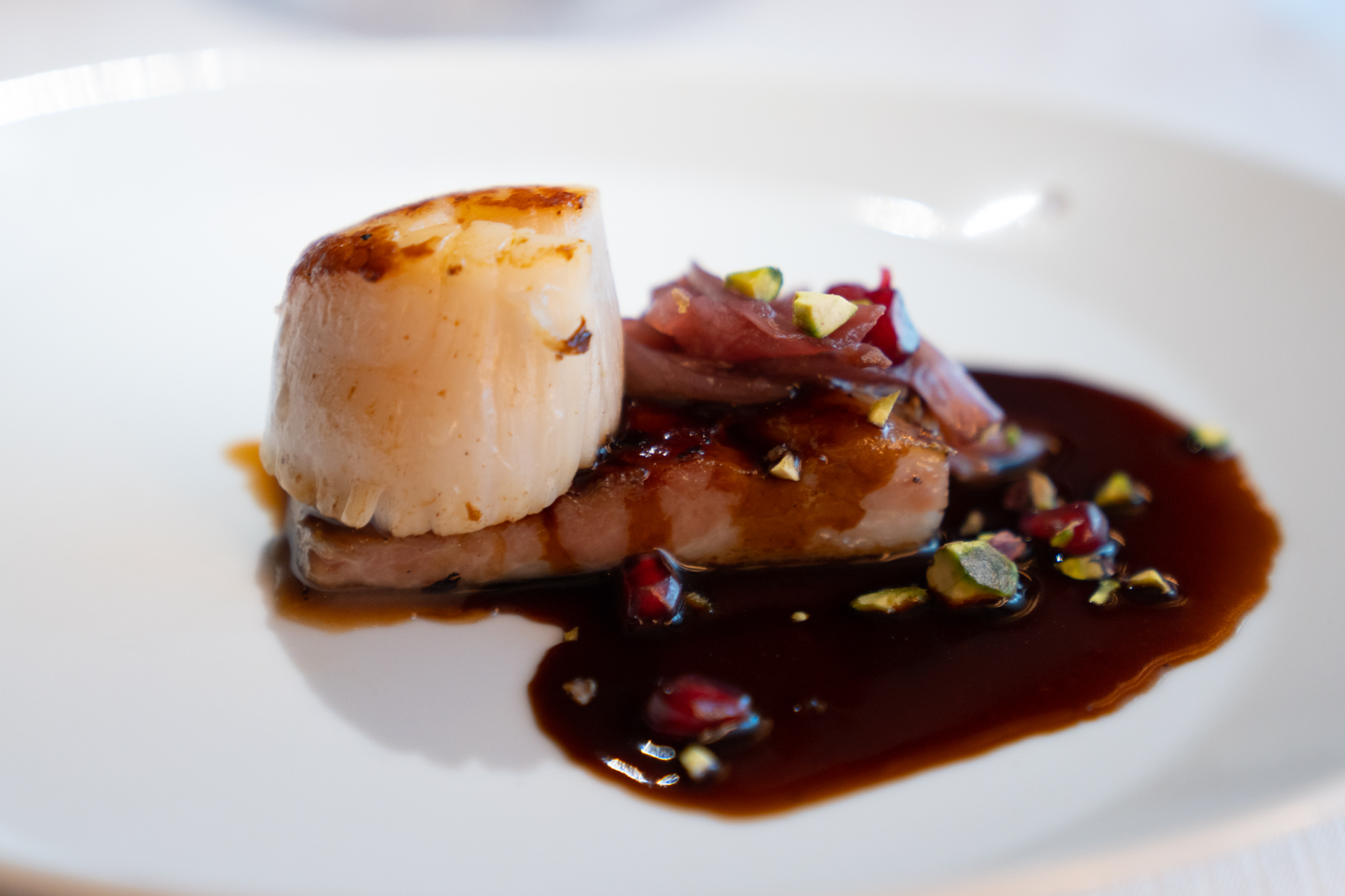 Seared Diver scallop  with cured pork belly, and orange and pomegranate sauce.