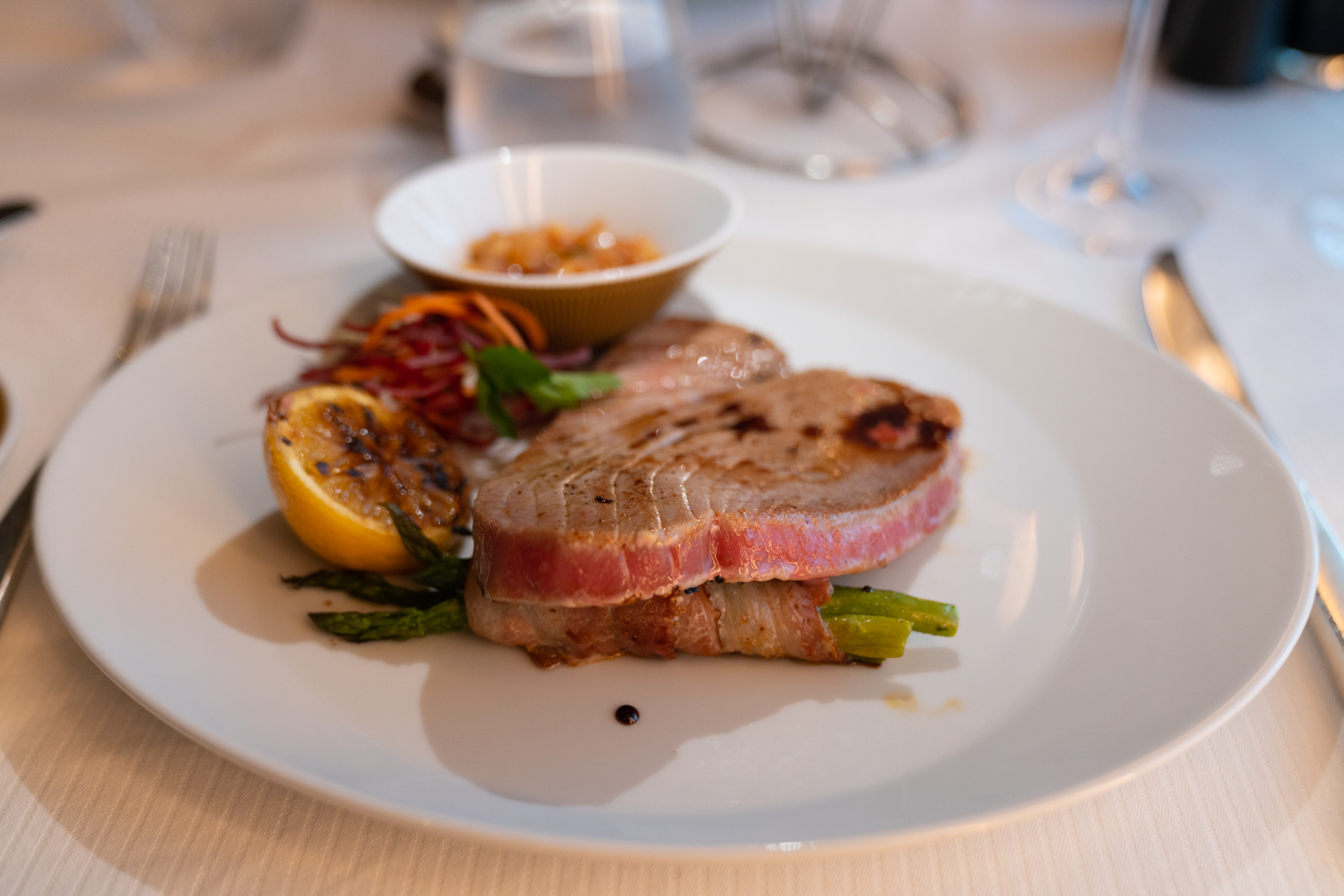 Spice-crusted seared Ahi tuna steak with pancetta asparagus, sweet soy glaze, and pineapple and chipotle salsa.