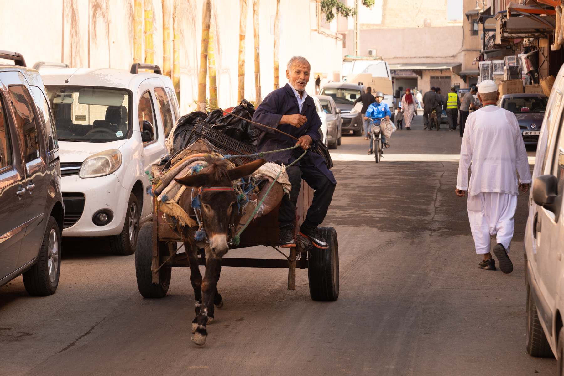 A man riding a cart being pulled by a donkey.