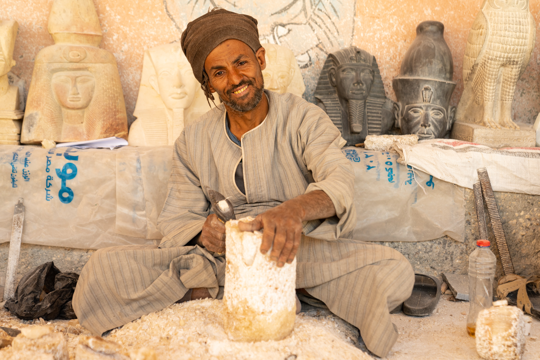 Local craftsman chiseling a slab of alabaster to make a pot.