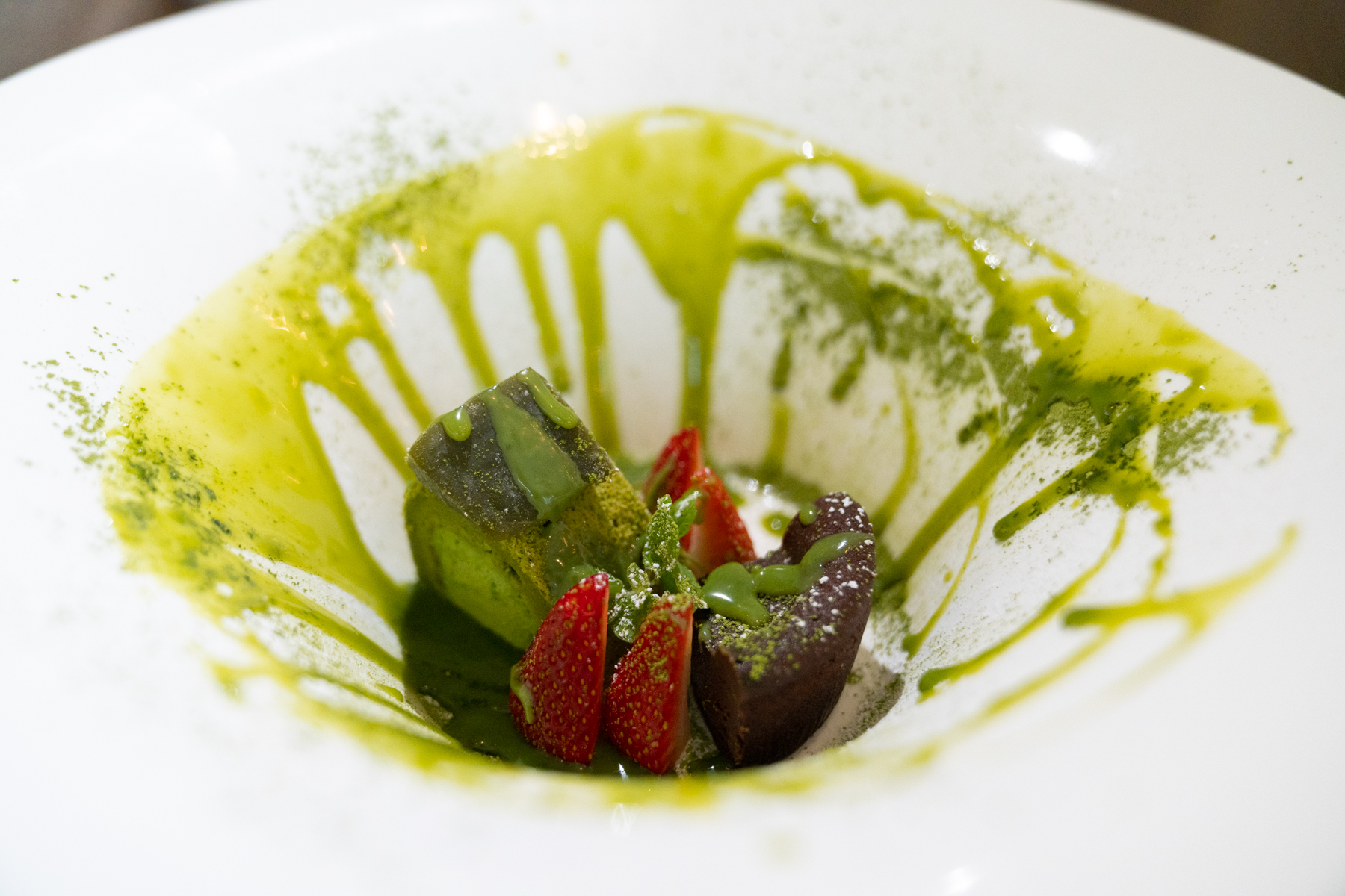 Dessert of chocolate, matcha cake, and strawberries.