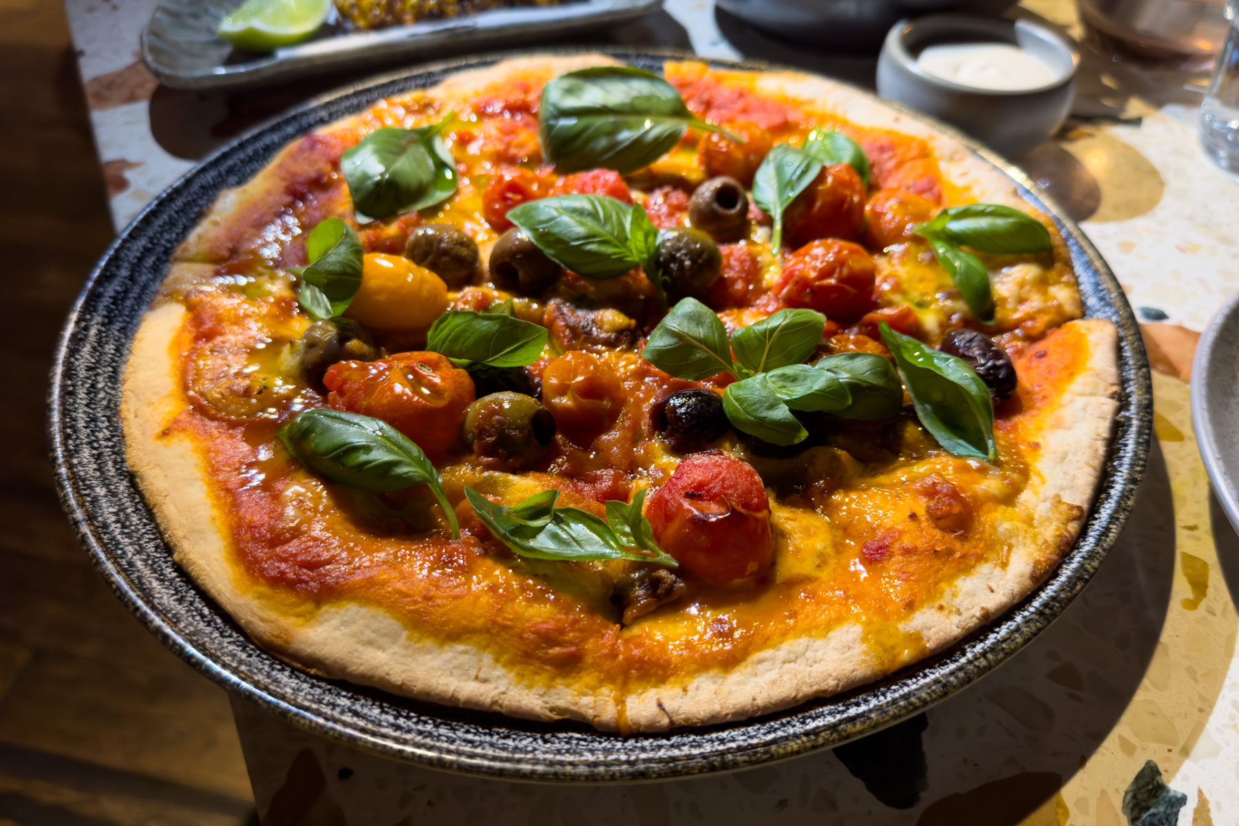 Flatbread with cherry tomatoes, burrata, olives, and basil.