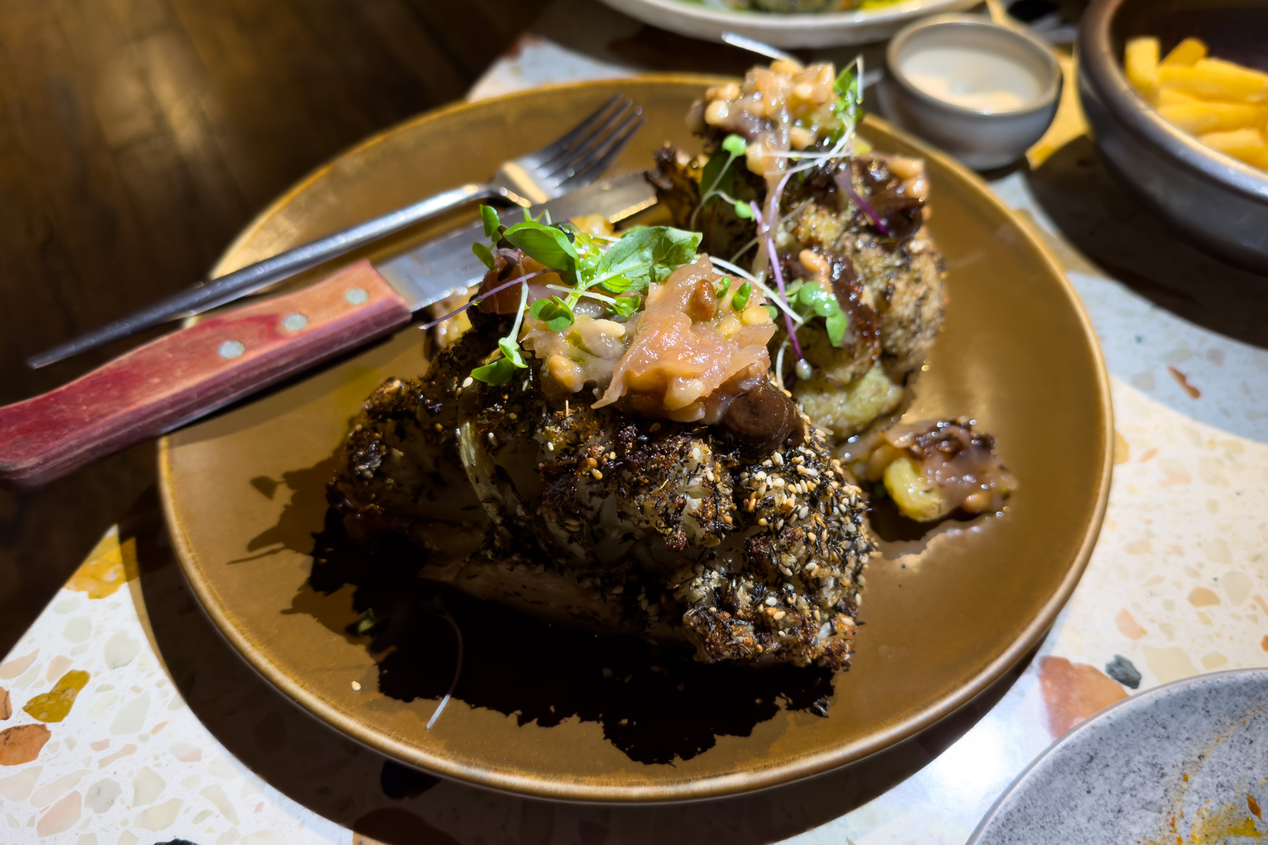 Za'atar roasted cauliflower with macadamia hummus, raisin emulsion, pine nuts, and agrodolce.