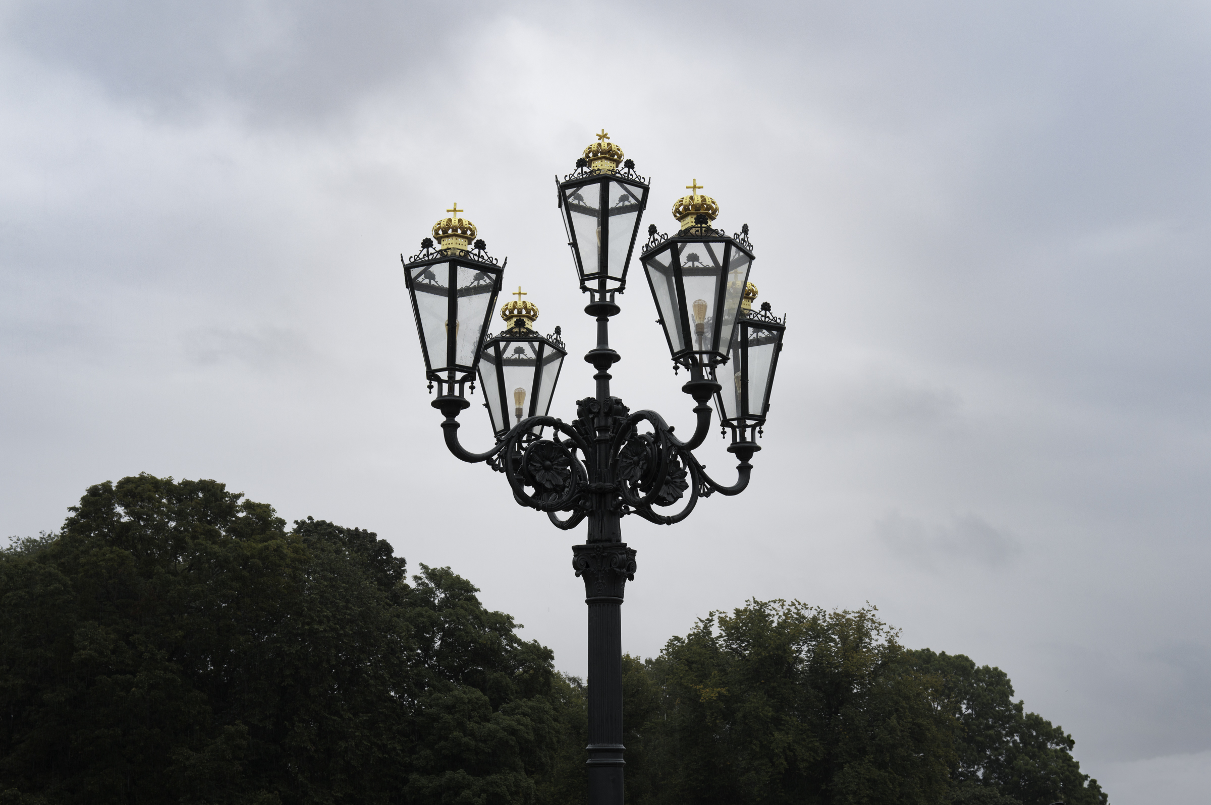 Ornate lamp post at the Royal Palace, with each lantern topped with a golden crown and cross, symbolising the Norwegian monarchy.